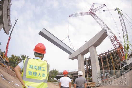 紅易-滬昆跨線橋跨滬昆高速公路主跨架梁施工現(xiàn)場，一節(jié)節(jié)鋼箱梁被吊起安裝。（記者 方陽 攝）